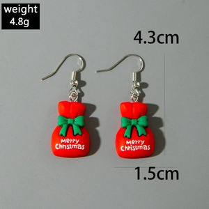 Détail de boucles d'oreilles sac cadeau rouge avec nœud vert et texte de Noël