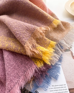 Close-up of soft knit plaid scarf texture with colorful tassels and fringe detail