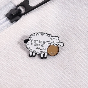 Detailed close-up of a white sheep enamel pin with Matthew 18:12 quote on fabric
