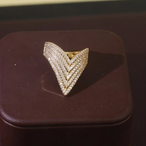 Close-up of golden V-shaped ring featuring pavé set zircons on a dark display box