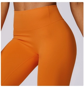 Close-up of bright orange high-waist yoga pants showing elastic fabric and seam texture