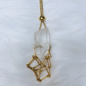 Detail of clear crystal pendant with gold geometric frame on soft white fur background