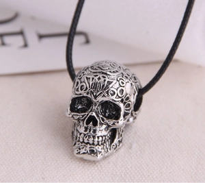 Close-up of vintage punk skull pendant with intricate engravings and black cord