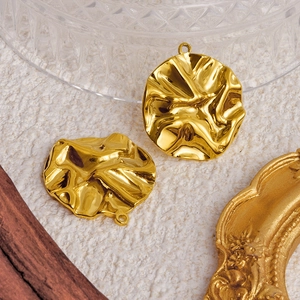 Deux pendentifs ronds dorés en acier inoxydable avec texture plissée sur fond vintage