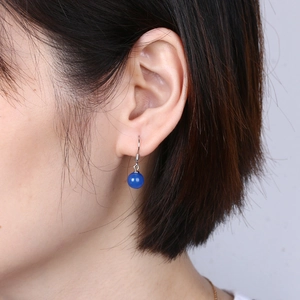 Close-up of model wearing retro silver hook earrings with translucent blue agate beads