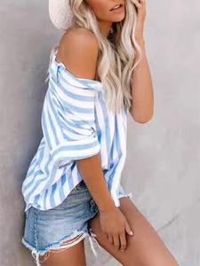 Side view of blue and white striped short-sleeve shirt paired with denim shorts and straw hat