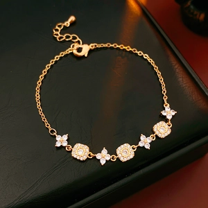 Macro shot of gold plated square and flower bracelet with sparkling crystals on leather