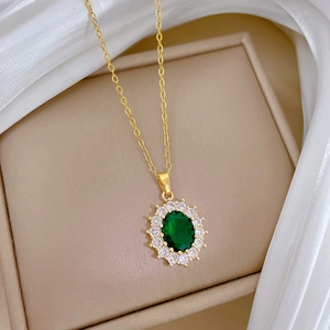 Close-up of golden necklace with oval green gemstone pendant on white satin background