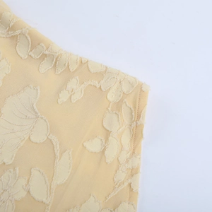 Dettaglio del top a schiena scoperta giallo tenue con trama in pizzo e tessuto jacquard