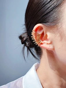 Close-up of a golden radial claw-shaped ear cuff on ear without piercing for women