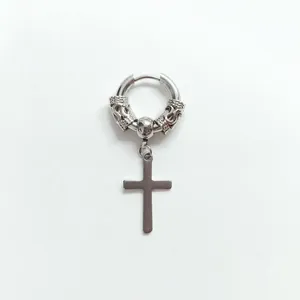 Detail of silver stainless steel earring with vintage engraved patterns and cross charm