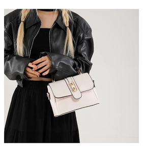 Detail shot of a cream white leather crossbody bag with a polished gold metallic clasp
