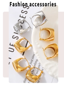 Close-up of chunky gold and silver square hoop earrings on a white ceramic tray