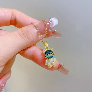 Gros plan du pendentif ours doré avec corps bleu et diamants étincelants sur un collier fin