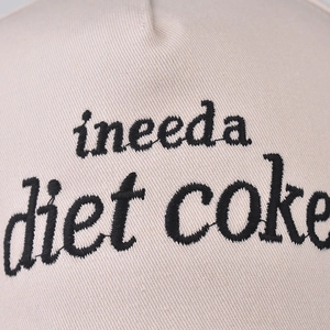 Beige cotton baseball cap with embroidered diet coke lettering and curved brim