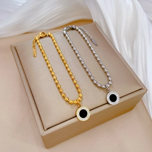 Gold and silver stainless steel beaded necklaces with black crystal pendants on a jewelry box