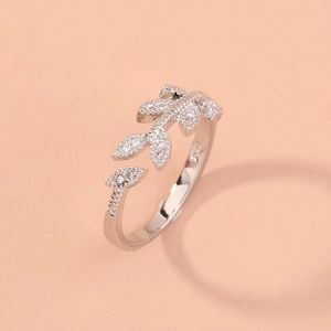 Detailed view of silver olive leaf ring with cubic zirconia on a warm background