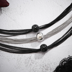 Detail of triple-layer punk choker with black ropes, silver chains, and metallic beads