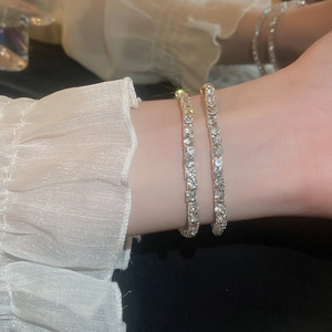 Gros plan de bracelets tennis argentés étincelants superposés sur un poignet avec volants