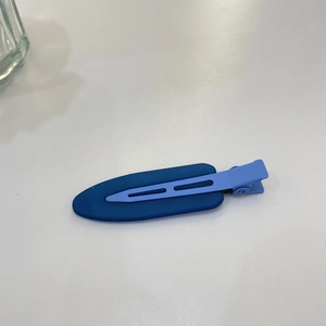 Detail view of a two-tone blue matte hair clip with modern minimalist oval design