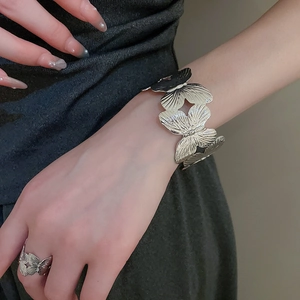 Close-up of silver metal leaf butterfly cuff bracelet and matching open ring set