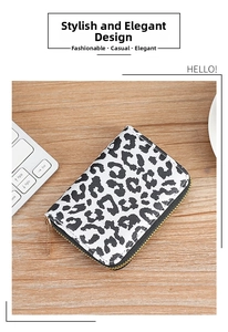 Close-up of leopard print card wallet with gold metal zipper on a wooden table
