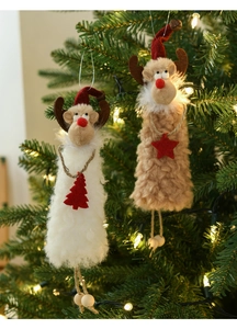 Close-up of plush reindeer ornaments with red hats hanging on a lit Christmas tree