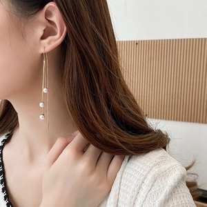 Detailed view of long gold tassel earrings with pearls on model for elegant style