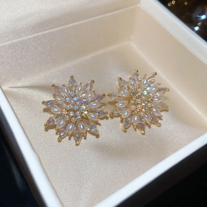 Detailed close-up of 18k gold-plated flower stud earrings with pearls and marquise zircons