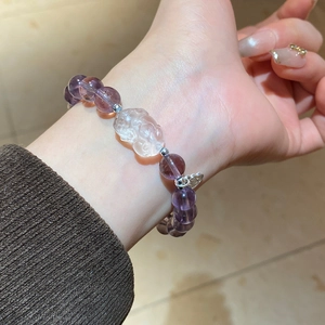 Detailed shot of amethyst bead bracelet with silver charms and carved centerpiece