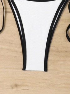 Detail of white triangle bikini top with wavy texture and black contrasting borders