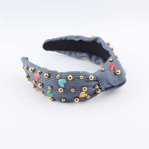 Close-up of striped fabric headband with gold studs and colorful heart charms details
