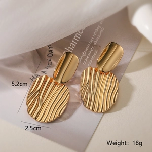 Close-up of geometric gold earrings with sand-textured ripple pendants and measurements