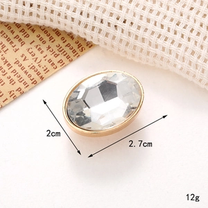 Macro shot of oval crystal gem charm with gold metal base and dimension details