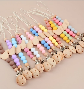 Close-up of wooden pacifier clips with colorful silicone beads and cute animal shapes