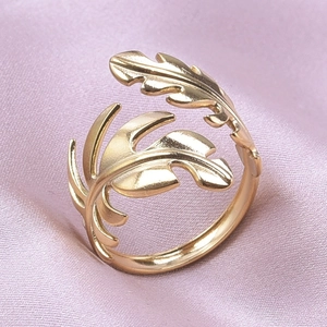 Macro detail of adjustable gold leaf ring featuring delicate feather texture on pink silk