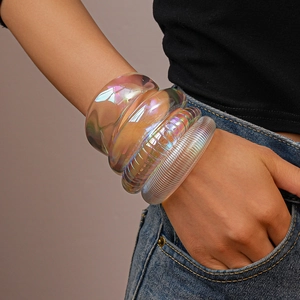 Macro shot of three stacked iridescent acrylic bangles with textured patterns and holographic glow