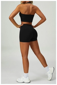 Back view of a black high-waisted yoga set featuring a halter vest and compression shorts