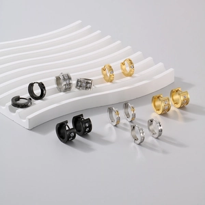 Macro display of C-shaped titanium steel earrings in gold silver and black with zircon