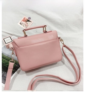 Pink piano note PU leather crossbody bag with top handle and gold hardware on white fabric