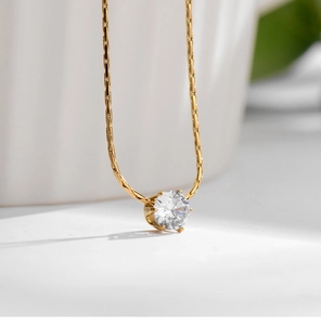Macro shot of a brilliant-cut zircon solitaire pendant on a 18K gold-plated bamboo chain