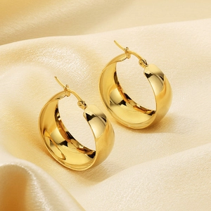 Polished 18k gold-plated wide hoop earrings on premium beige silk fabric background