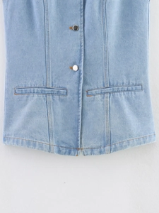 Detail of light blue denim vest showing contrast stitching and silver metal buttons