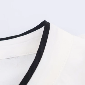 Detail of white shirt neckline featuring black contrast piping and precise stitching