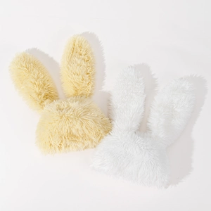 Detail view of soft plush bunny ear hats in cream and white faux fur textures