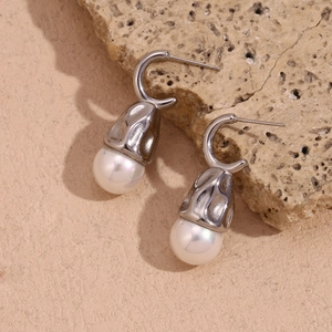 Macro detail of teardrop pearl earrings with hammered silver texture on stone