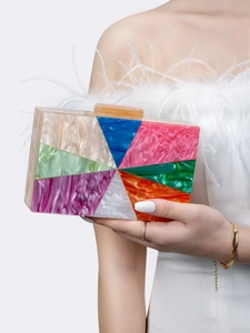 Model holding a multicolor geometric patchwork acrylic clutch bag with pearl textures