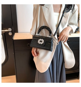 Detail of elegant black crocodile pattern bag with a sparkling square crystal buckle