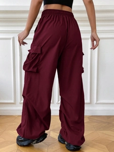 Detail of high-waisted burgundy cargo pants featuring side flap pockets and a wide-leg cut