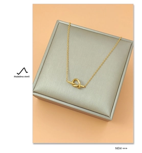 Detail view of a minimalist gold stainless steel necklace with a geometric knot pendant
